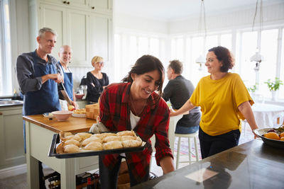 Happy friends preparing food together in kitchen at home