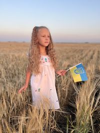 Portrait of a girl  standing on the field against clear sky