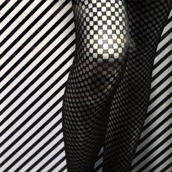 Midsection of woman in stockings against striped wall
