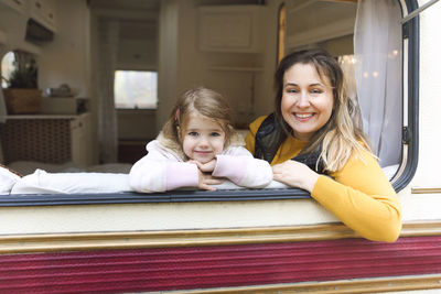 Portrait of happy mother and daughter sitting at motor home