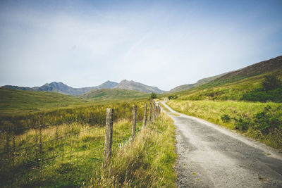 Road amidst green landscape against sky