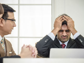 Colleague looking at frustrated businessman in office
