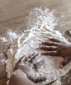 Cropped hands on kid flattening dough on table