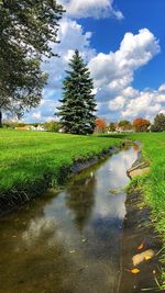 Canal amidst field against sky