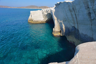 Panoramic view of cliff by sea against blue sky