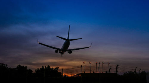 Low angle view of silhouette airplane against sky at dusk