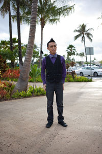 Full length portrait of young man standing on palm tree