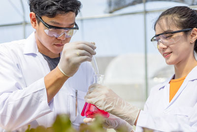 Low angle view of scientists holding flask and pipette