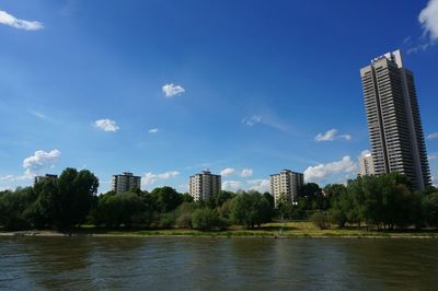 Scenic view of river by buildings against sky