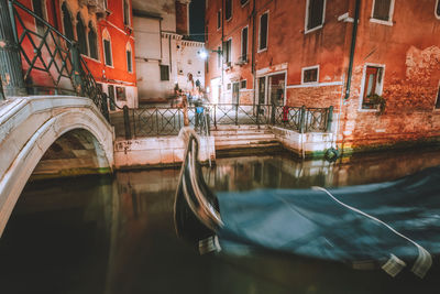 Canal amidst buildings in city at night