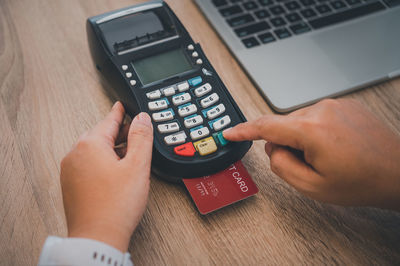 Cropped hands of person using calculator at table