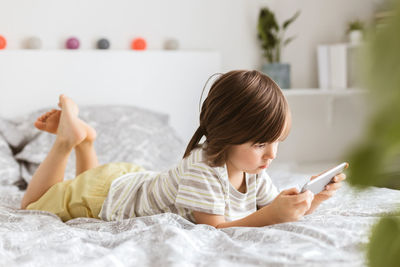 A little boy of four years lies on the bed and plays a smartphone. children use technology.