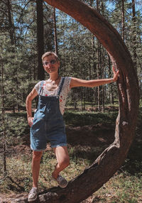 Full length portrait of smiling young woman in forest