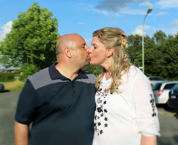 Rear view of couple kissing against sky