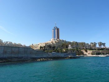 View of buildings by sea against blue sky