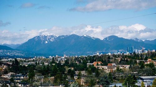 Aerial view of townscape and mountains against sky