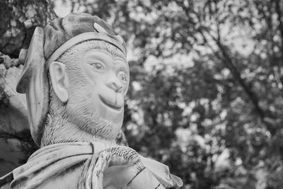 Close-up portrait of statue against trees