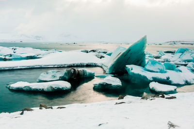 Scenic view of ice bergs floating on sea against cloudy sky during sunset