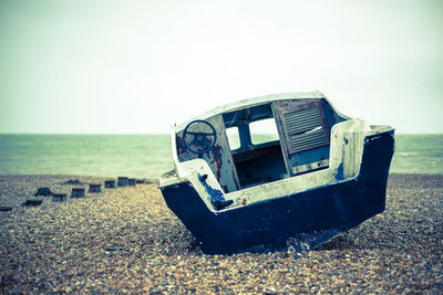 Abandoned car on beach against clear sky