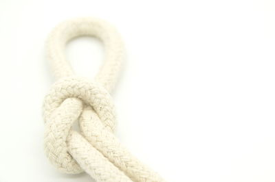 Close-up of rope tied on white background