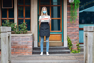 Caucasian waitress woman wearing medical mask and sorry we're closed. coronavirus covid-19 pandemic