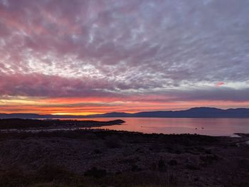 Scenic view of sea against dramatic sky during sunset