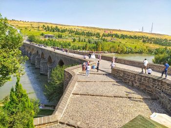 People on bridge over river against sky