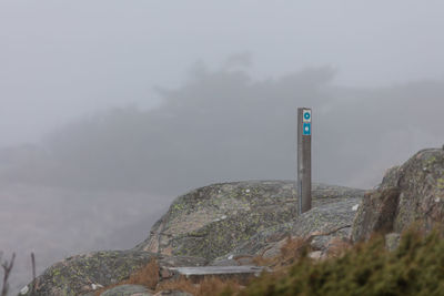 Arrow sign on mountain against sky