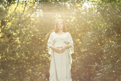 Young woman standing against trees