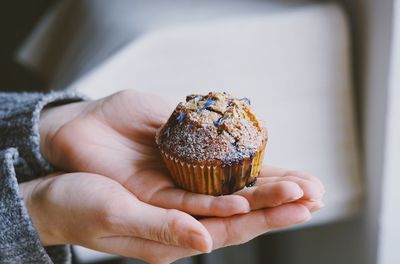 Cropped hands holding cupcake at home