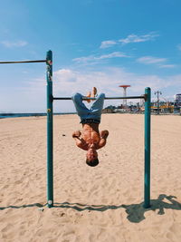 Full length of men jumping on beach against sky