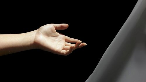 Cropped hand of woman gesturing against colored background