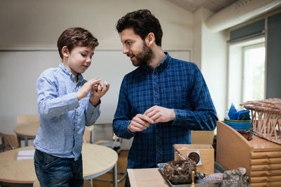 Teacher assisting male student in making project at school