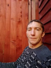 Portrait of young man standing against wall