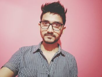 Portrait of young man standing against wall