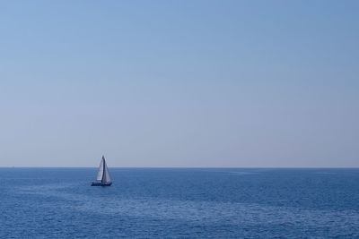 Sailboat sailing in sea against clear sky