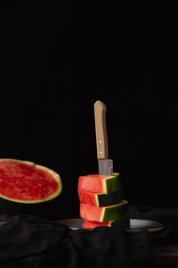 Close-up of fruits served on table against black background