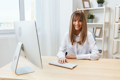 Portrait of young woman using laptop at table