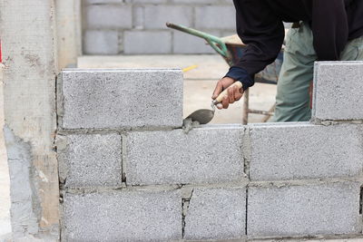 Midsection of construction worker making concrete wall