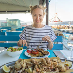 Portrait of woman holding food on table