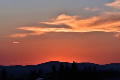 Scenic view of silhouette mountains against orange sky