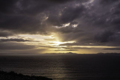 Scenic view of sea against dramatic sky during sunset