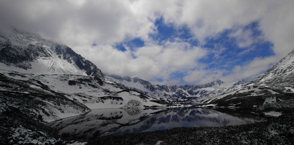 Snow covered mountains against cloudy sky