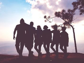 Silhouette people standing on land against sky during sunset