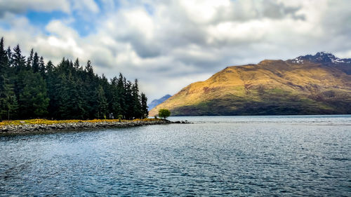Scenic view of lake by trees against sky