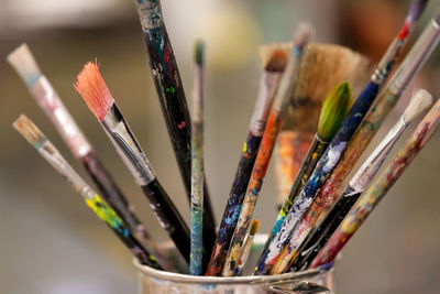 Many dirty worn artist brushes in a jar