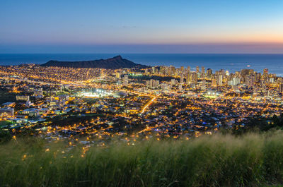 High angle view of illuminated buildings by sea against sky