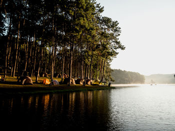 People by lake against sky