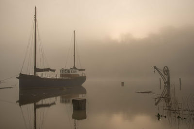 Sailboats moored on lake against sky during sunset