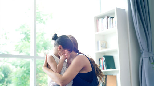 Woman consoling daughter crying at home